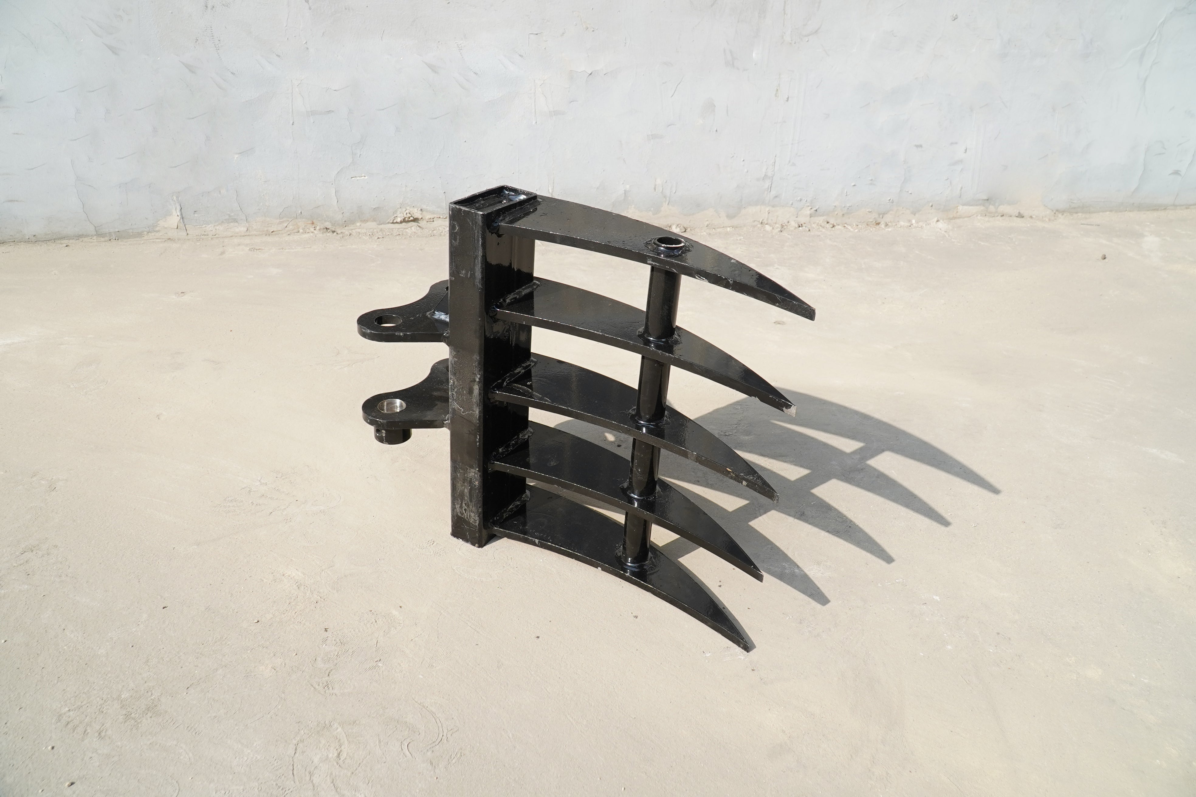 Rippa Australia black metal Excavator Rake attachment with four curved tines on concrete surface