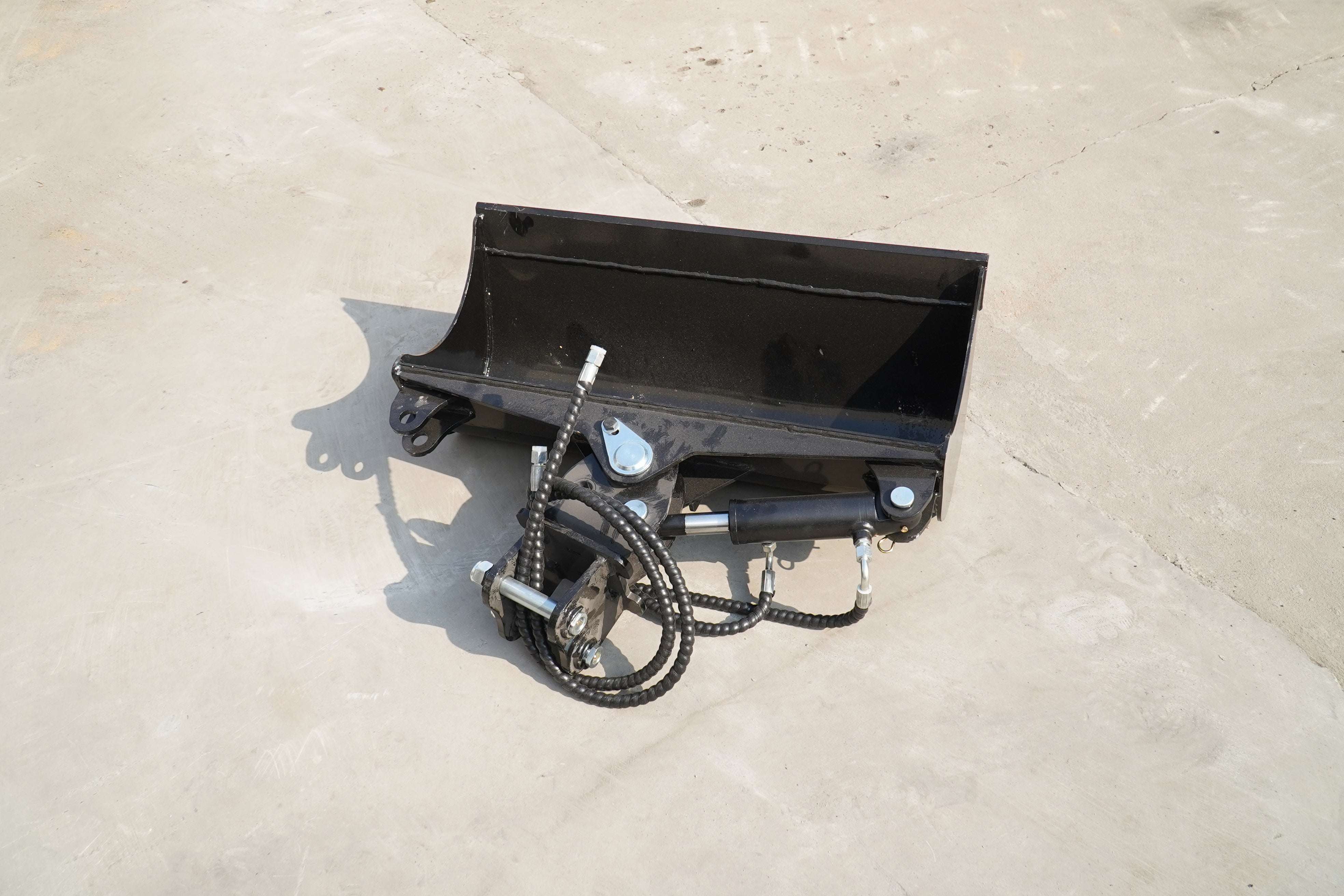 Rippa Australia black excavator tilt bucket attachment with hydraulic components on concrete